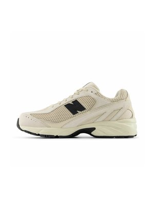 Baskets athlétiques beige avec panneaux en mesh et en suède, logo noir "N" sur le côté, semelle épaisse crème avec crampons noirs, vues de profil gauche.