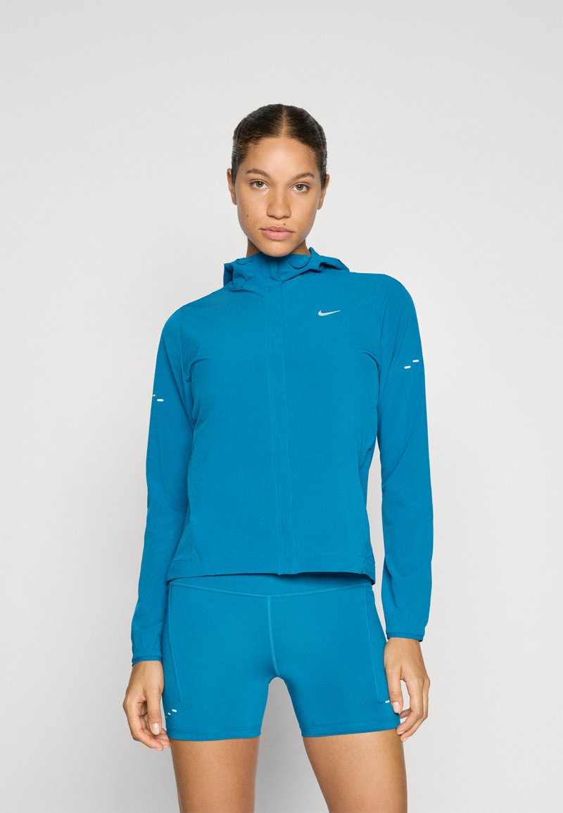 Himmelblaues Zip-Jacke mit Kapuze und langen Ärmeln, mit reflektierenden Akzenten, kombiniert mit passenden Shorts, aus leichtem Stoff gefertigt.