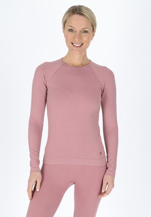 Langarm sporttop in zachtroze, geribbelde stof. Heeft een ronde halslijn en een slim fit silhouet, gecombineerd met bijpassende geribbelde leggings.
