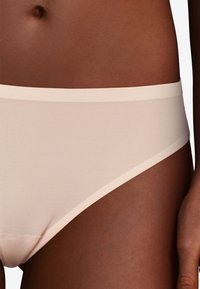 Beige seamless underwear with a smooth texture, low-rise design, and a soft elastic waistband, featuring minimalistic style and no visible seams.