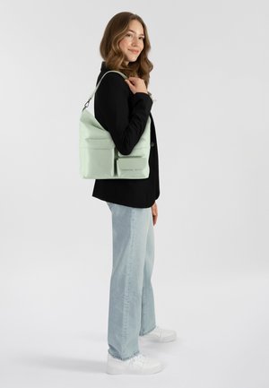 Sac à épaule en nylon vert clair avec deux poches avant, bandoulière réglable, texture douce et design minimaliste.
