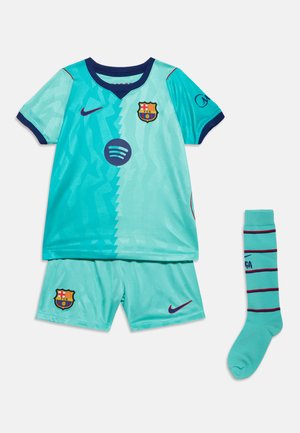 Maillot de football FC Barcelone bleu clair et turquoise, short assorti, et une chaussette avec des détails bleu marine et rouge et logos visibles.