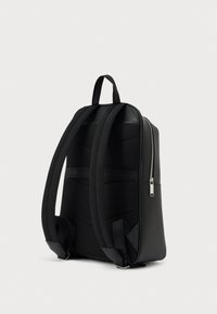 Mochila negra con un diseño elegante, equipada con correas acolchadas, respaldo texturizado y una cremallera metálica en un lado.