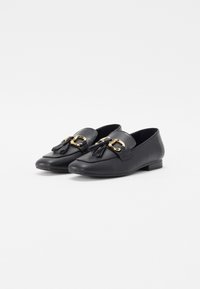 Sorte skinnloafers med flat såle, med en gullfarget spenne og dusker foran for detaljer. Glatt tekstur.