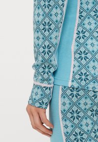 Μπλε μακρυμάνικη μπλούζα με γεωμετρικό σχέδιο σε πιο σκουρόχρωμες αποχρώσεις, με αντίθετο ανοιχτόχρωμο περιθώριο κατά μήκος των ραφών.