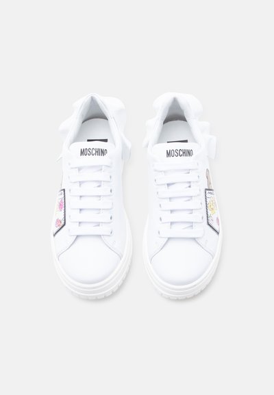 Λευκά sneakers Moschino με παχιά σόλα, κορδόνια μπροστά και πολύχρωμα σχέδια καρτούν σε patches στις εξωτερικές πλευρές.