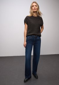 Ciemnoszary krótki sweter z dzianiny z krótkim rękawem, zestawiony z szerokimi spodniami dżinsowymi w ciemnoniebieskim kolorze. Gładka tekstura, luźny krój i standardowe detale dżinsowe.