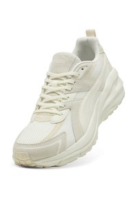 Scarpa sportiva bianca con tomaia in rete e suede, punta arrotondata, suola texturizzata e chiusura con lacci. Accentuata da dettagli del logo discreti.
