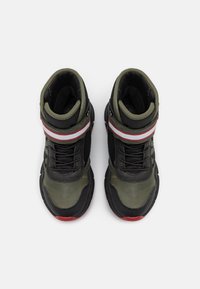 Zapatillas altas negras y oliva con un upper de cuero texturizado y malla, que presentan un acento a rayas rojas y blancas en el tobillo.