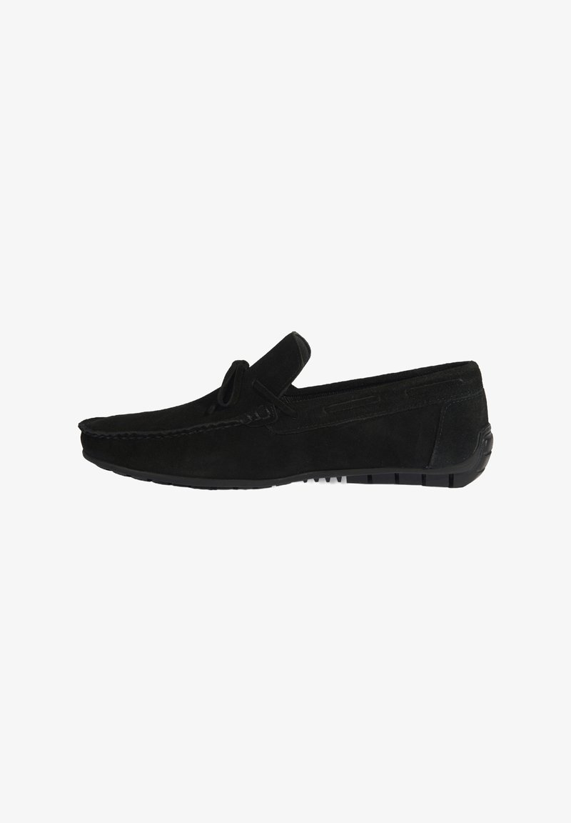 Mocassin en suède noir avec un bout arrondi, des coutures décoratives et une semelle en caoutchouc texturée pour une meilleure adhérence. Inserts élastiques sur les côtés.
