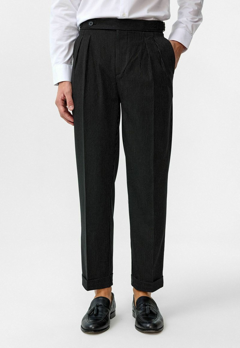 Zwarte krijtstreepbroek met een geplooid front, smalle pijpen, zijzakken en een tailleband met een enkele knoopsluiting.