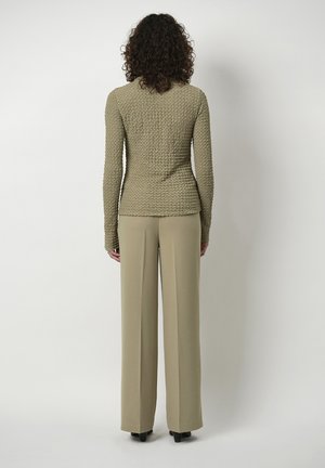 Beige textuur lange mouwen top met fitted taille, gecombineerd met wijde lichtbeige broek. Eenvoudig ontwerp, geen zichtbare versieringen.