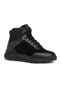 Botas de senderismo negras que combinan gamuza texturizada y cuero sintético liso. Incluyen un cierre con cordones en la parte delantera, un collar acolchado y una suela resistente.