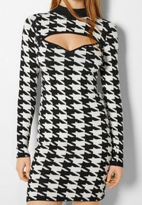 Svart och vit houndstooth bodycon klänning med långa ärmar, featuring en utskärning vid bröstet och en hög halsringning.