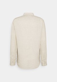 Chemise beige à manches longues avec boutons, vue de dos avec un col standard et des poignets boutonnés sur un fond uni.