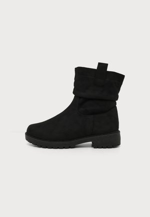 Botte noire mi-mollet avec revers plié, languette de traction et semelle épaisse crantée pour un usage en extérieur ou décontracté.