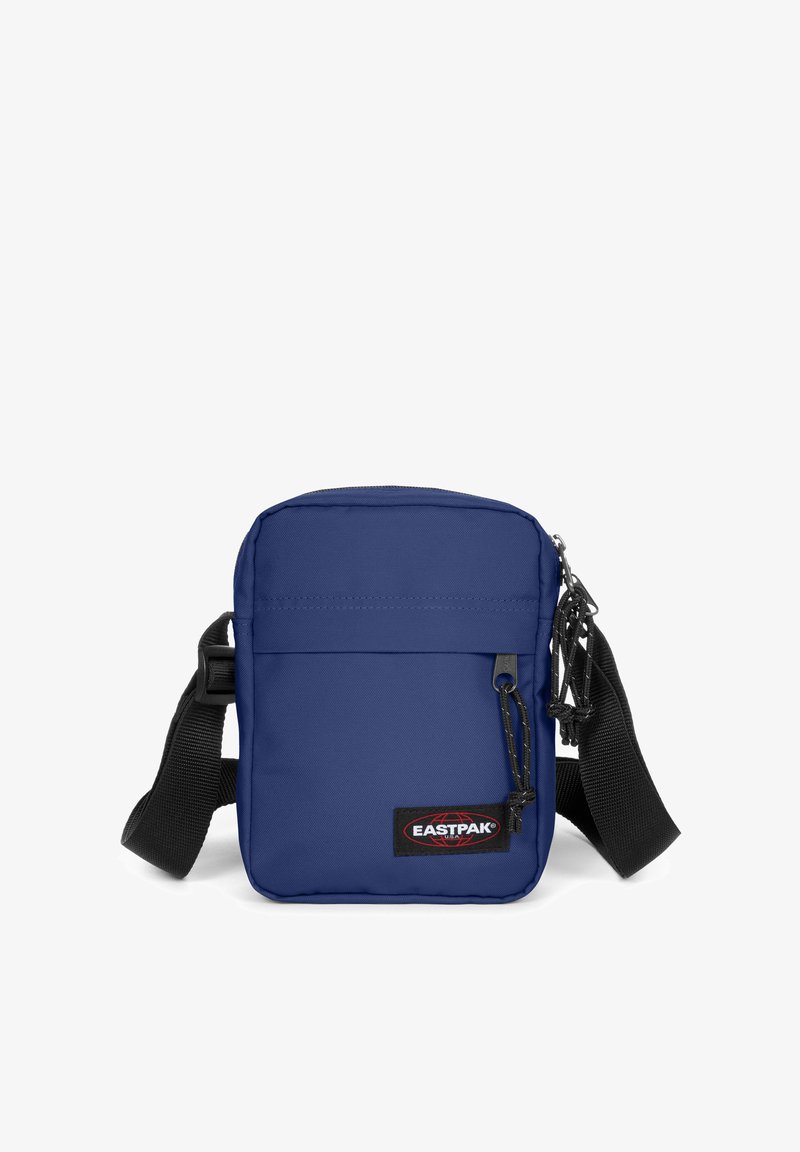 Námořnická modrá obdélníková crossbody taška s černým popruhem, obsahující přední kapsu, zipové zapínání a logo Eastpak v pravém dolním rohu.