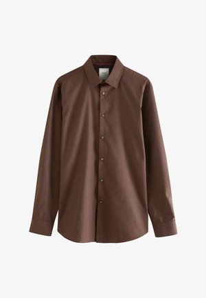 Mann trägt dunkelbraunes Hemd mit Knöpfen, schwarzen Gürtel, schwarze Anzughose und schwarze Loafers mit goldener Schnalle.