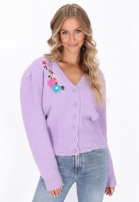 Lila gestrickte Strickjacke mit V-Ausschnitt, geripptem Saum und sechs Knöpfen, verziert mit bunten gestickten Blumen auf einer Schulter.