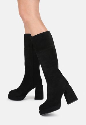 Black suede knee-high boots with a chunky high heel and platform, featuring a smooth texture and minimalistic design.