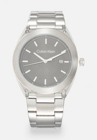 Reloj de acero inoxidable plateado con un dial gris, marcadores de hora blancos, ventana de fecha a las 3 en punto y una pulsera de eslabones metálicos pulidos.