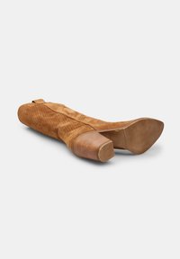 Bota de ante marrón hasta la rodilla con una superficie texturizada, punta cuadrada y tacón apilado. Presenta un cierre lateral con cremallera.