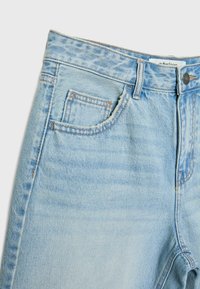 Svijetloplave traperice s izbljeđenom teksturom, s prednjim džepom, petljama za pojas i tradicionalnim šavovima.