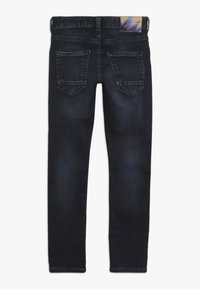 Jeans oscuros de corte ajustado con bolsillos traseros, un desgastado sutil y una etiqueta con la marca en la cintura.