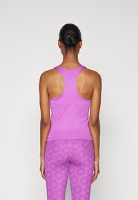 Lilla treningstopp med racerback-design, laget av glatt stoff. Kombinert med mønstrede lilla leggings med blomsterprint.