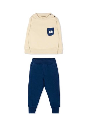 Camicia beige a maniche lunghe con tasca blu navy e bottoni sulla spalla abbinata a pantaloni jogger blu navy con vita elastica per bambino piccolo.