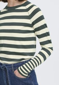 Camisa de manga larga a rayas en verde oscuro y crema, con cuello redondo y puños acanalados. Tejido de punto suave con un ajuste holgado.