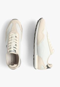 Baskets beige et gris clair avec des matériaux en mesh et en daim, design à lacets, bout rond, semelle texturée et branding subtil sur la languette.