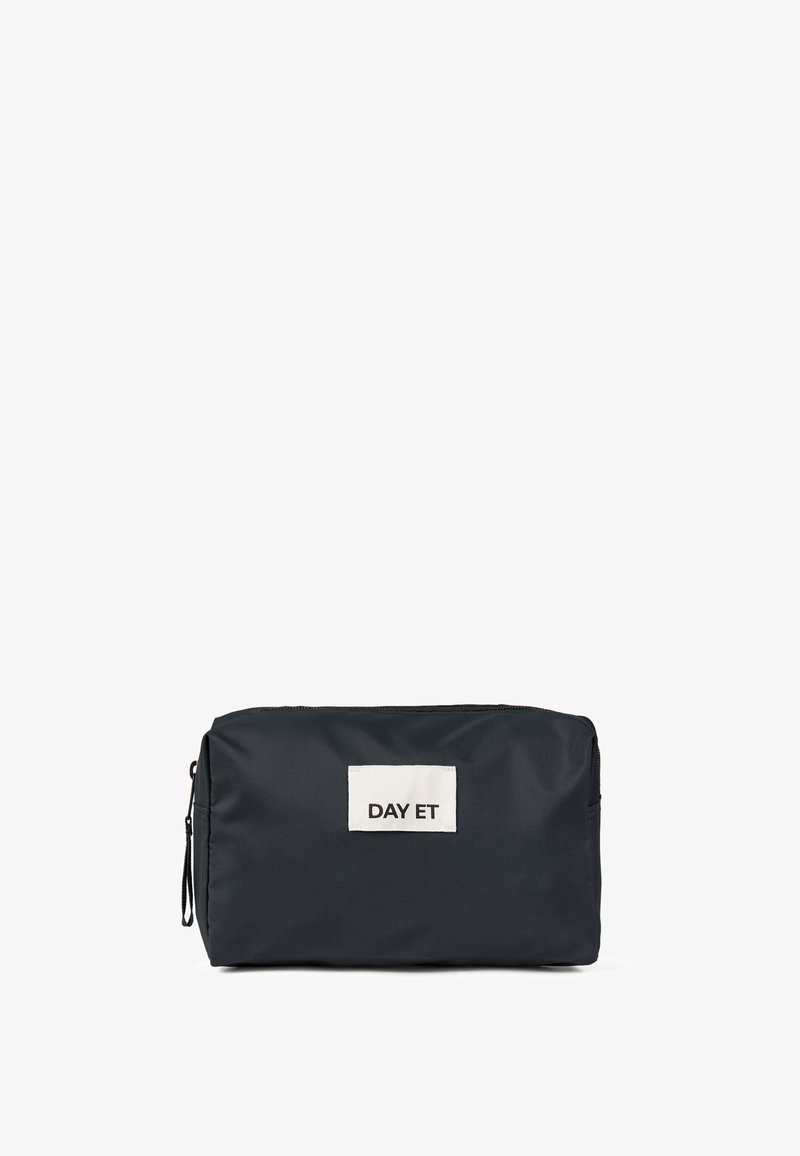 Trousse de maquillage en nylon noir de forme rectangulaire, avec une étiquette en tissu blanc à l'avant affichant "DAY ET". Fermeture éclair, texture lisse.