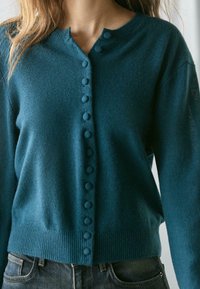 Turquoise gebreid vest met een ronde hals, voorzien van een rij knopen en een geribbelde zoom. Gemaakt van een zachte, gestructureerde stof.