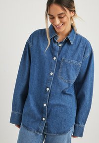 Jeanshemd in Hellblau mit durchgehender Knopfleiste, Kragen-Design, einer Brusttasche und langen Ärmeln. Weicher Stoff mit lockerem Schnitt.