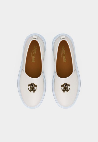 Λευκά παπούτσια χωρίς κορδόνια με ανοιχτό μπλε σόλες και μεταλλικό λογότυπο σε σχήμα δερματίνης φιδιού στην κορυφή, με την επωνυμία "Roberto Cavalli" στο εσωτερικό.