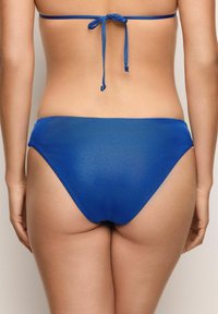 Blå bikiniunderdel med en slät textur, högskurna benöppningar och minimal täckning. Har en justerbar knytbakdesign.