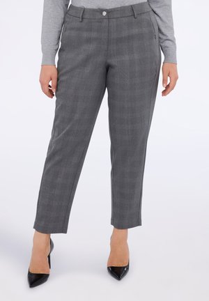 Pantalons à carreaux gris avec une coupe ajustée, présentés avec une fermeture à bouton et des poches latérales, associés à des escarpins noirs à bout pointu.