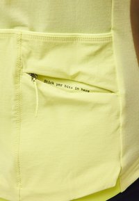 Τσέπη από ανοιχτό κίτρινο ύφασμα με μερικώς ανοιχτό φερμουάρ, που αποκαλύπτει μαύρο κείμενο μέσα που λέει "Βάλε τα πράγματά σου εδώ."