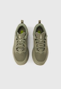 Chaussures de sport vertes avec une tige en mesh texturé, fermeture à lacets, col rembourré et semelle en caoutchouc. Conçues pour le confort et le soutien.