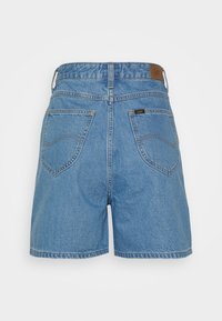 Vaaleansiniset farkkushortsit, joissa on korkeavyötäröinen malli, kaksi takataskua koristeellisilla saumoilla ja nahkainen logopläkki vyötäröllä.