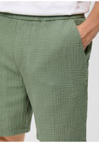 Groene gestreepte shorts met een elastische tailleband, voorzien van subtiele ruitpatronen en zijzakken. Zachte stof met een licht gekreukt uiterlijk.