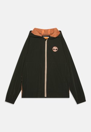 Veste verte foncée avec doublure en maille orange pour la capuche, fermeture éclair sur le devant, et poches latérales. Présente un logo orange sur la poitrine gauche et des poignets élastiques.