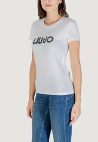 T-shirt bianco in cotone con logo in scrittura nera "LIU JO" e maniche corte. Il taglio è casual, con scollatura rotonda e texture morbida.