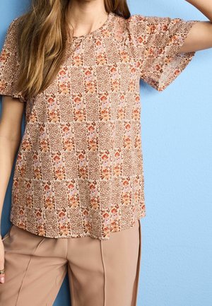 Blusa a maniche corte in tessuto leggero con sfondo beige e motivi floreali e astratti in toni terrosi, scollatura rotonda.
