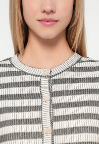 Svart- og hvitstripet cardigan med rund hals, med knapper foran og teksturert strikket stoff. Glatt, lett materiale.