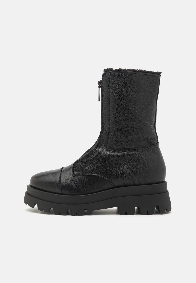 Botte mi-mollet en cuir noir avec semelle crantée épaisse, bout renforcé, fermeture éclair sur le devant et doublure en polaire visible sur la bordure supérieure.