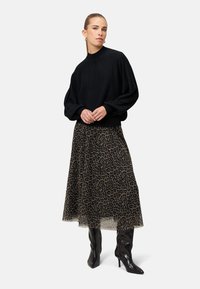 Czarny dzianinowy sweter z długimi rękawami i wysokim kołnierzem, w połączeniu z plisowaną spódnicą w leoparda i czarnymi wysokimi botkami.