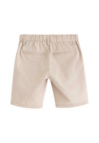 Beige shorts i bomull, med ett elastiskt midjeband och två bakfickor med sömnadsdetaljer. Slät textur och med längd till mitten av låret.