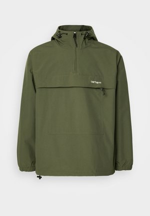 Olive green anorak jacket made of soft, lightweight fabric. Features a half-zip closure, adjustable hood, and front pocket. Elastic cuffs.